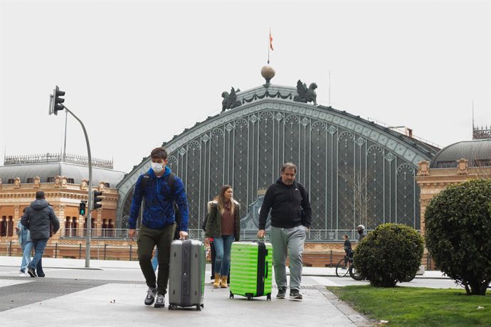Varios turistas con maletas se protegen con mascarillas a su salida de la Estación de Atocha.