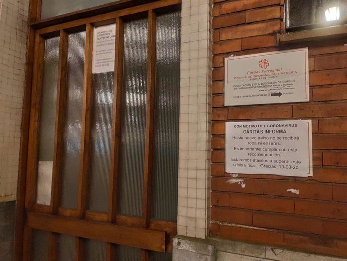 Cartel de Cáritas parroquial en la iglesia del Corazón de María de Oviedo, con medidas relacionadas con el coronavirus.