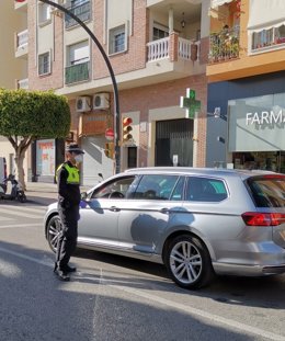 Un agente de la Policía Local de Rincón de la Victoria (Málaga) informando a un conductor de las medidas del estado de alarma ante el COVID-19