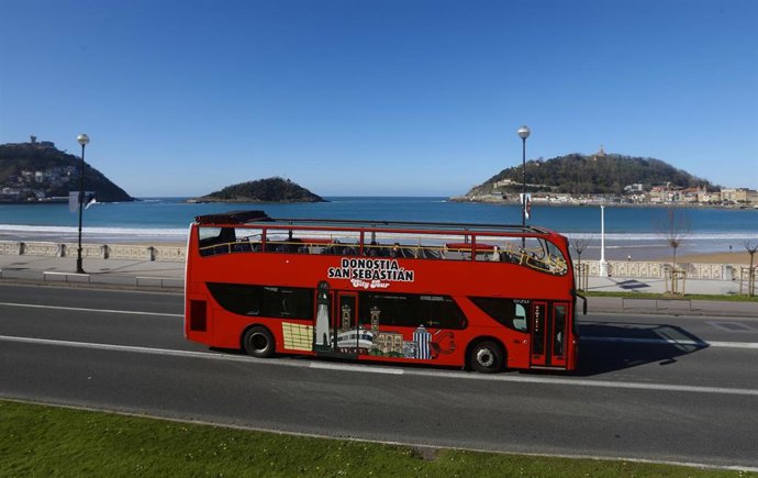 Un autobús turístico en una carretera junto a la Playa de la Concha en San Sebastián tras la alerta sanitaria por el coronavirus y la entrada en vigor de medidas adoptadas este sábado por el Gobierno Vasco, como el cierre de locales hosteleros, en San S