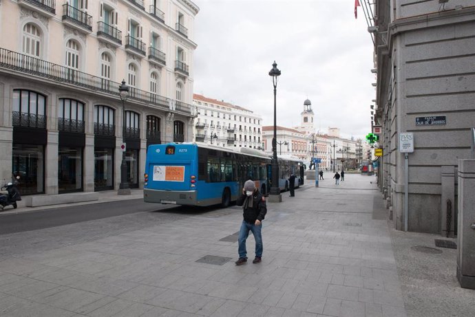 Una persona con mascarilla anda por la calle Calle Alcalá junto a la turística Puerta del Sol madrileña vacía durante el estado de alarma decretado por el coronavirus, en Madrid (España), a 16 de marzo de 2020.