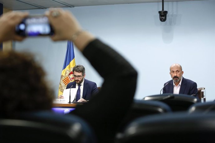 Una responsable del Departament de Comunicació del Govern d'Andorra fotografia amb el mbil els ministres Eric Jover i Joan Martínez Benazet, en la roda de premsa.