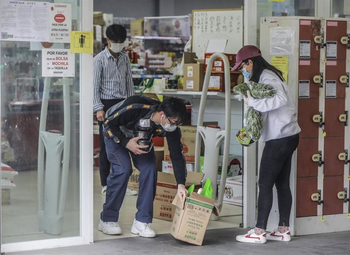 Personas de procedencia asiática salen de realizar sus compras en un establecimiento de una cadena de supermercados chinos durante el primer día laborable del estado de alarma decretado por el coronavirus, en Valencia (Comunidad Valenciana, España)