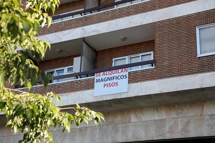 En el balcón de un piso, se ve colgado un cartel en el que se lee 'Se alquilan magníficos pisos'.