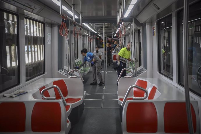 Dos trabajadores limpian los pasamanos y barandillas del metro para combatir la propagación de la epidemia del coronavirus Covid-19