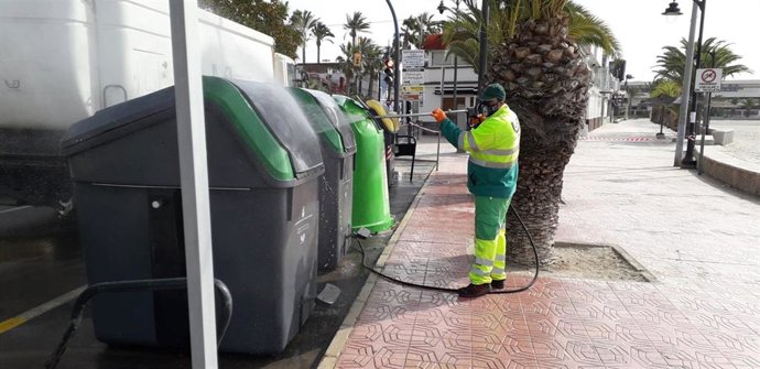 Un operario limpia contenedores instalados en la vía pública