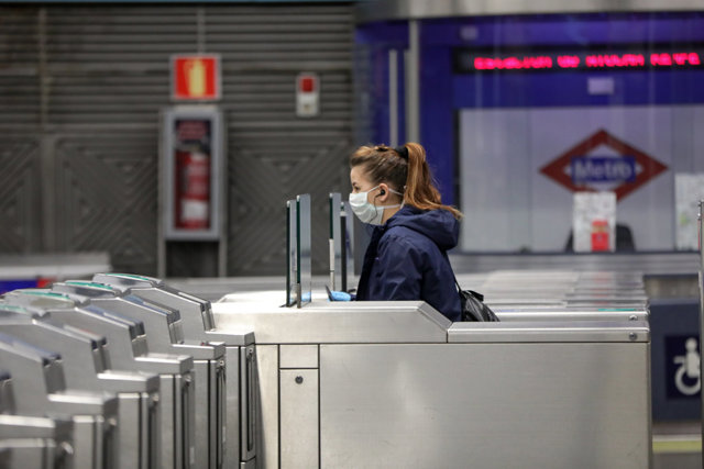 Una mujer con mascarilla pasa por los torniquetes de la estación de metro de Atocha durante el tercer día laborable desde que se decretó el estado de alarma a consecuencia del coronavirus, en Madrid (España), a 18 de marzo de 2020.