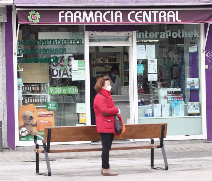 Una mujer protegida con mascarilla pasa al lado de una farmacia abierta en el tercer día laborable del estado de alarma por coronavirus en España, en Madrid (España), a 18 de marzo de 2020.