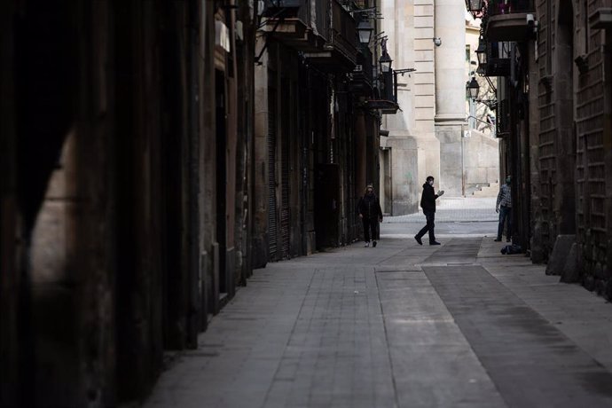 Una persona camina per un carrer de Barcelona durant el tercer dia laborable de l'estat d'alarma per coronavirus, a Barcelona/Catalunya (Espanya) a 18 de mar de 2020.