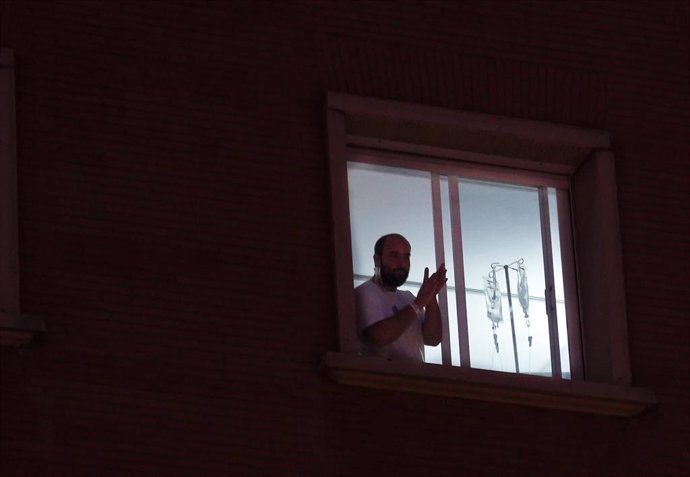Un enfermo  sale a la ventana del hospital Virgen del Rocio de Sevilla, para aplaudir a los sanitarios. Sevilla a 18 de marzo 2019