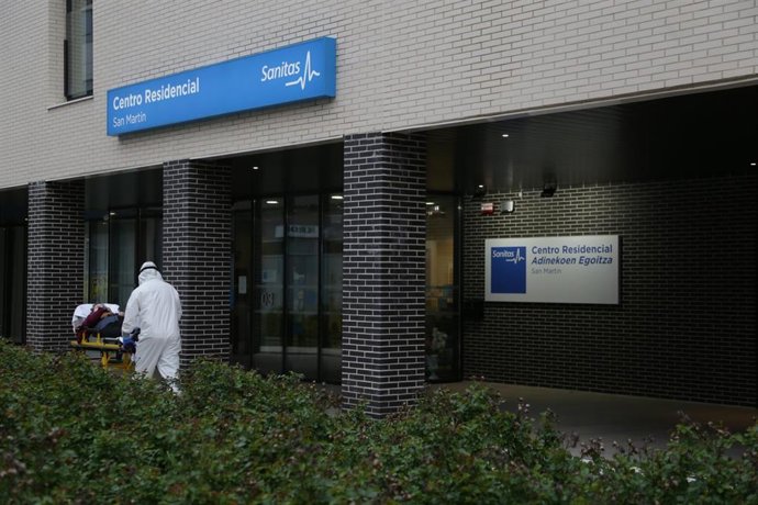 Un sanitario protegido con un traje, guantes y mascarilla, sale con una camilla en la que lleva a una persona de la residencia Sanitas San Martín donde han fallecido 8 personas por coronavirus y otros 45 ancianos contagiados permanecen en aislamiento, e