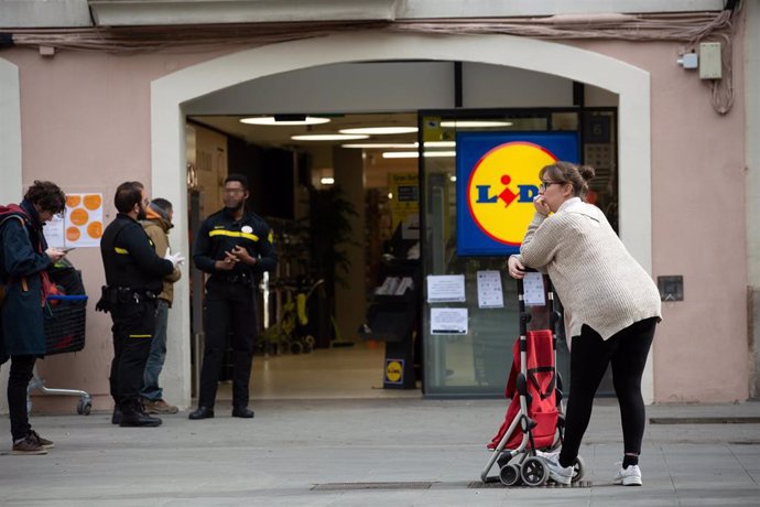 Una mujer espera con su carro de la compra a poder entrar a un supermercado Lidl tras las medidas de aforo impuestas por seguridad, durante el segundo día laborable del estado de alarma por el coronavirus, en Barcelona/Catalunya (España)