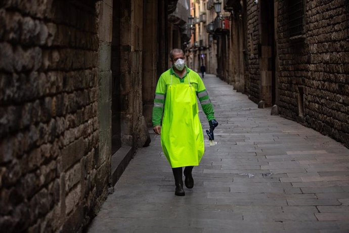 Un trabajador con mascarilla anda por una calle de Barcelona durante el tercer día laborable del estado de alarma por coronavirus, en Barcelona/Catalunya (España) a 18 de marzo de 2020.