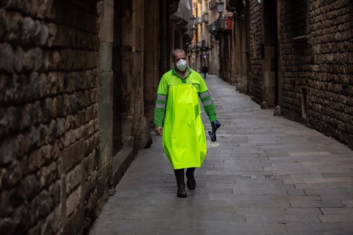 Un treballador amb mascarilla camina per un carrer de Barcelona durant el tercer dia laborable de l'estat d'alarma per coronavirus, a Barcelona/Catalunya (Espanya) a 18 de mar de 2020.