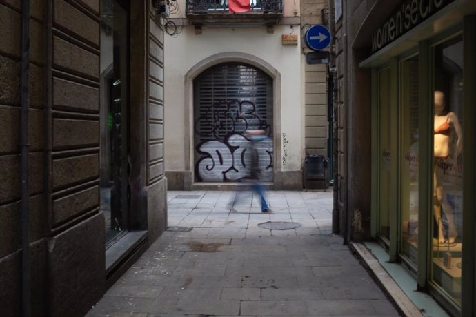 Una persona camina per un carrer de Barcelona durant el tercer dia laborable de l'estat d'alarma per coronavirus, a Barcelona/Catalunya (Espanya) a 18 de mar de 2020.