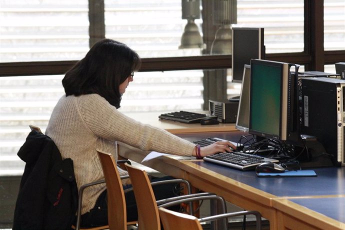Una estudiante consultando un ordenador.