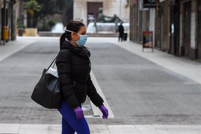 Una mujer camina con mascarilla y guantes de látex durante el cuarto día del estado de alarma por coronavirus, en Valencia/Comunidad Valenciana (España) a 19 de marzo de 2020.