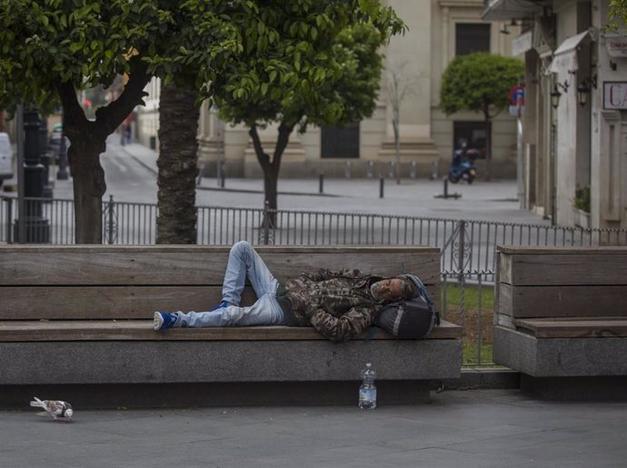 Una persona sense llar dorm en un banc de l'avd. de la Constitució, durant el quart dia laborable de l'estat d'alarma per coronavirus, (Covid-19). A Sevilla, (Andalusia, Espanya), a 19 de mar de 2020.