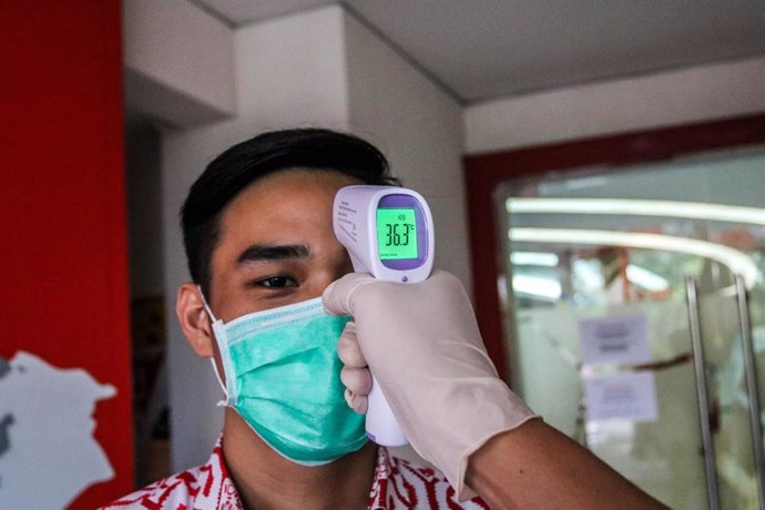 Personal sanitario toma la temperatura a un trabajador indonesio. 