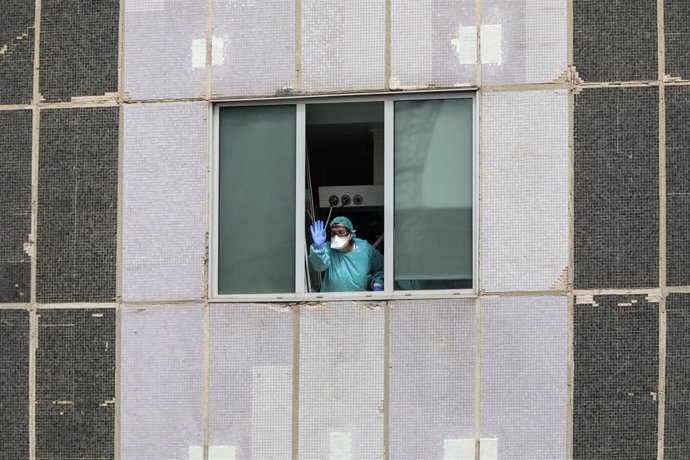 Una sanitaria del Hospital de La Paz totalmente protegida saluda y agradece el apoyo desde una de las ventanas del centro donde se lucha contra el coronavirus, en Madrid (España), a 18 de marzo de 2020.