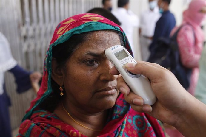 Un funcionarios de las autoridades sanitarias de Bangladesh toma la temperatura a una mujer en Daca, la capital del país.