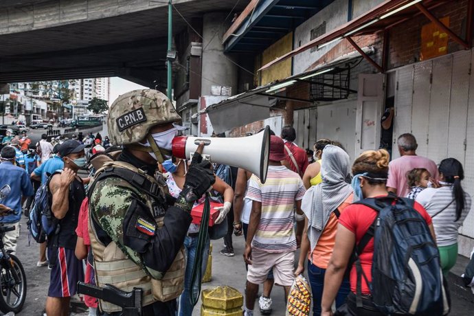 Un agente de la Fuerza Boliviariana de Venezuela explica a la población que debe regresar a sus hogares a causa de la cuarentena decetada por el Gobierno.