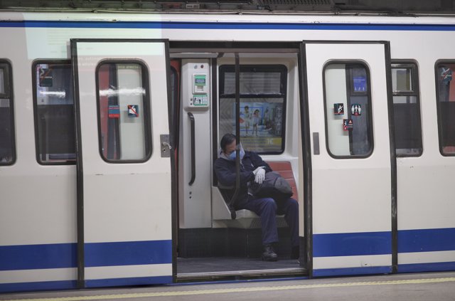 Un hombre protegido con mascarilla y sentado dentro del metro en Atocha 