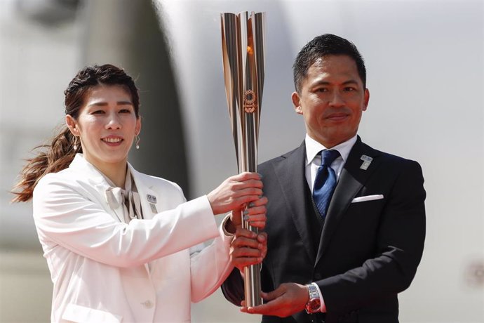 Saori Yoshida y Tadahiro Nomura sostienen la llama olímpica a su llegada a Japón
