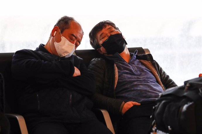 Pasajeros protegidos con mascarilla esperan en el Aeropuerto Adolfo Suárez Madrid-Barajas