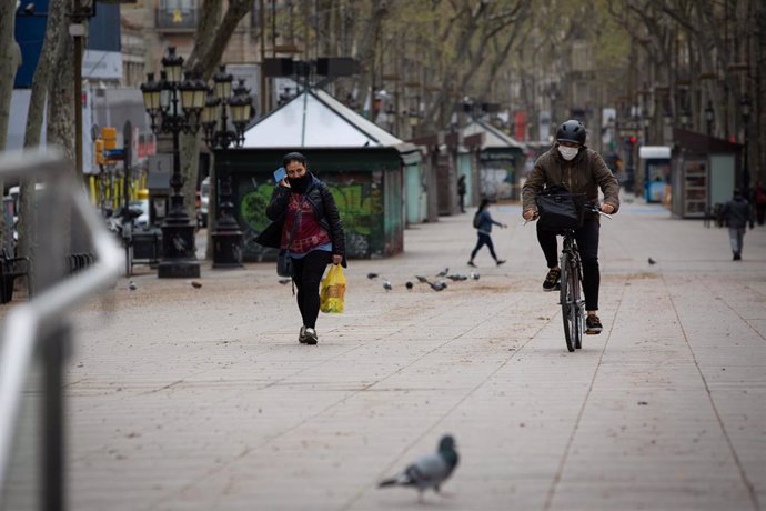 Una persona munta amb bicicleta i es protegeix amb una mascarilla durant el segon dia laborable de l'estat d'alarma pel coronavirus, a Barcelona (Espanya), a 17 de mar de 2020.
