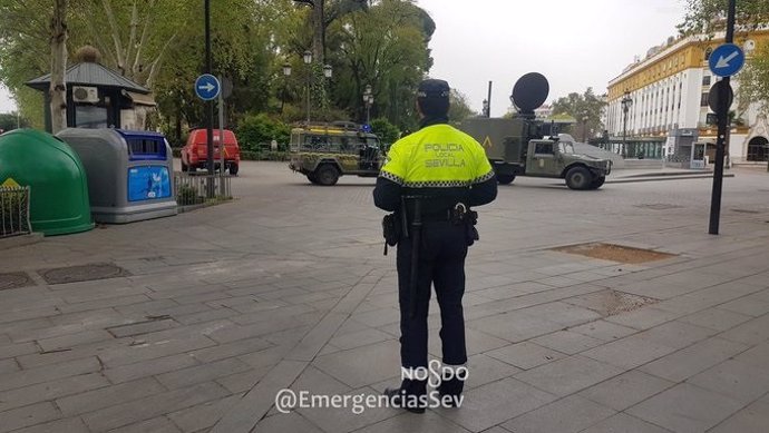 Un policía local de Sevilla en Puerta Jerez, ante varios vehículos de la UME