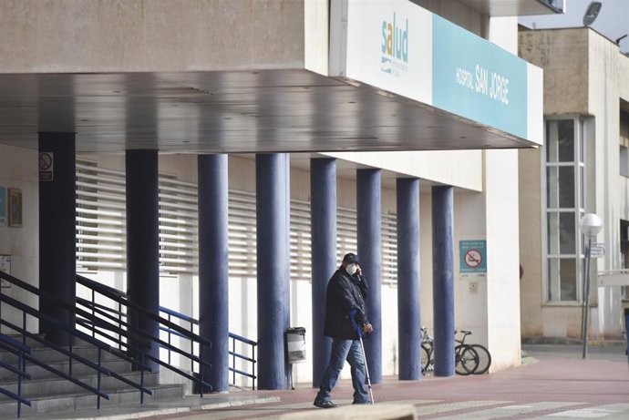 Un hombre protegido con mascarilla camina por la zona exterior perteneciente al Hospital San Jorge en Huesca durante el cuarto día laboral en el estado de alarma en el país por el coronavirus, en Huesca, Aragón (España), a 19 de marzo de 2020.
