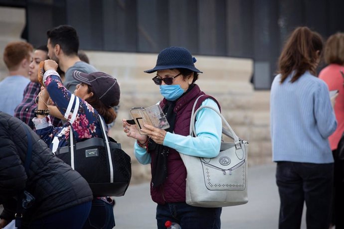 Una mujer utiliza su móvil en zonas cercanas a la Sagrada Familia protegida con mascarilla ante el avance del coronavirus en Barcelona