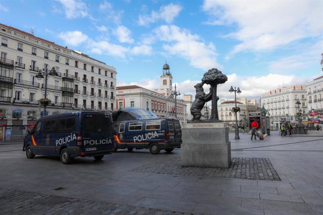 Furgones de la policía vigilan la Puerta del Sol para controlar quién pasea por el centro de Madrid tras la declaración de estado de alarma