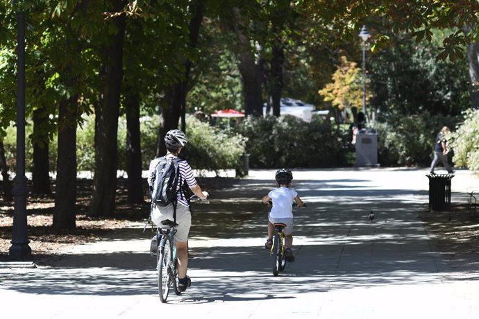 Una madre y su hijo pasean en bicicleta en un parque de Madrid.