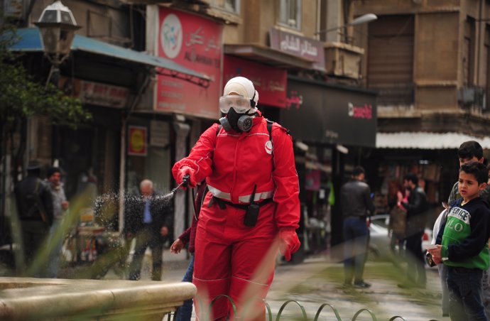 21 March 2020, Syria, Damascus: A Syrian worker wearing a protective face mask disinfects a street, as a preventive measure amid fears of the spread of the Coronavirus (COVID-19). Photo: Omar Estwani/APA Images via ZUMA Wire/dpa