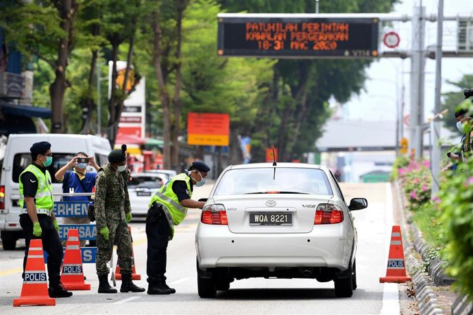 22 March 2020, Malaysia, Kuala Lumpur: Secuity officers stops a car at a checkpoint amid strict movement restrictions as part of the measures aiming to slow the spread of Coronavirus. Photo: Hazim Mohammad/BERNAMA/dpa