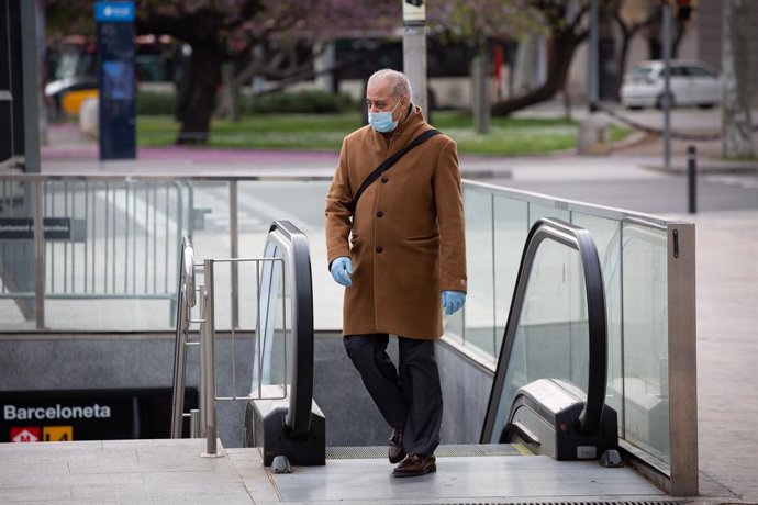Un home protegit amb una mascarilla i guants de ltex surt del metre durant el segon dia laborable de l'estat d'alarma pel coronavirus, a Barcelona/Catalunya (Espanya), a 17 de mar de 2020.