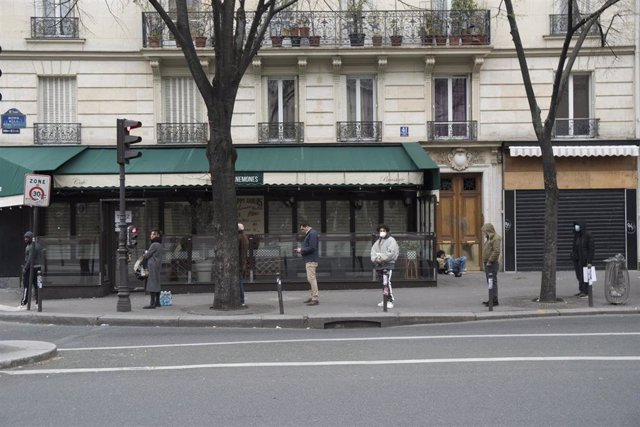 Personas con mascarilla en una fila en París