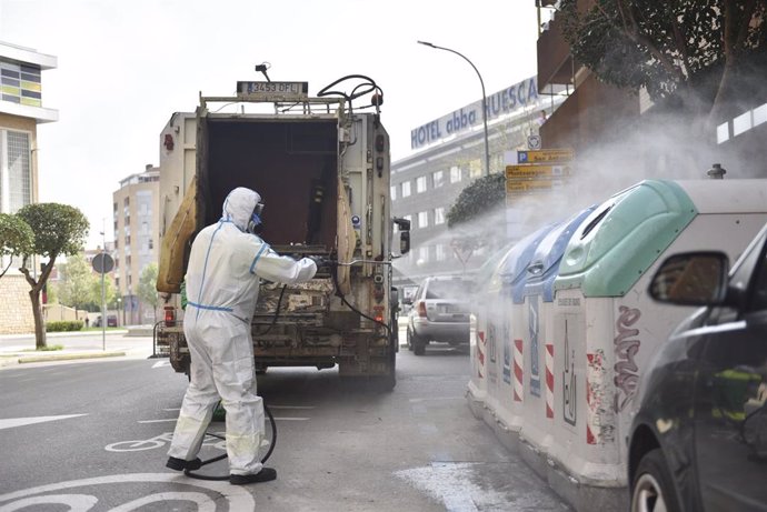 Un trabajador protegido de cuerpo entero desinfecta los cubos de basura y de reciclaje en el cuarto día laborable del estado de alarma por coronavirus, en Huesca, Aragón (España), a 19 de marzo de 2020.