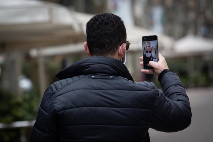 Un hombre protegido con mascarilla se hace un selfie.