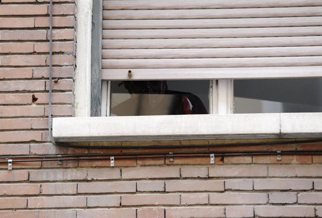 Un hombre con mascarilla en la ventana de un edificio Madrid