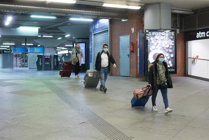 Tres personas con maletas y protegidas con mascarillas en la Estación de Atocha.