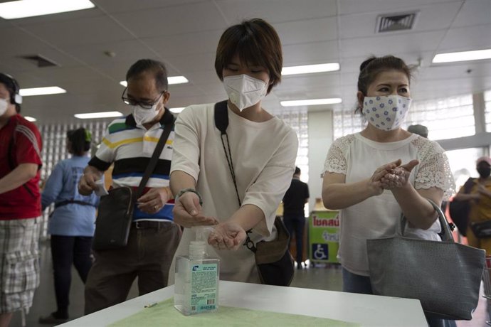 Un grupo de personas se desinfectan las manos con gel antes de entrar a un supermercado en Bangkok, Tailandia.