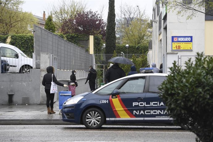 Un coche de policía nacional vigila la entrada a un supermercado AhorraMas en el barrio madrileño de Usera
