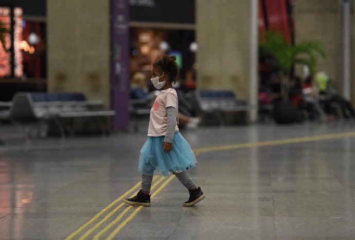 Una niña con mascarilla por el coronavirus pasea por el aeropuerto de Río de Janeiro