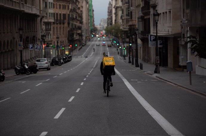 Un treballador de Glovo amb bicicleta per un carrer de Barcelona, prcticament buida durant el primer dia laborable de la segona setmana des que es va decretar l'estat d'alarma, a Barcelona/Catalunya (Espanya) a 23 de mar de 2020.