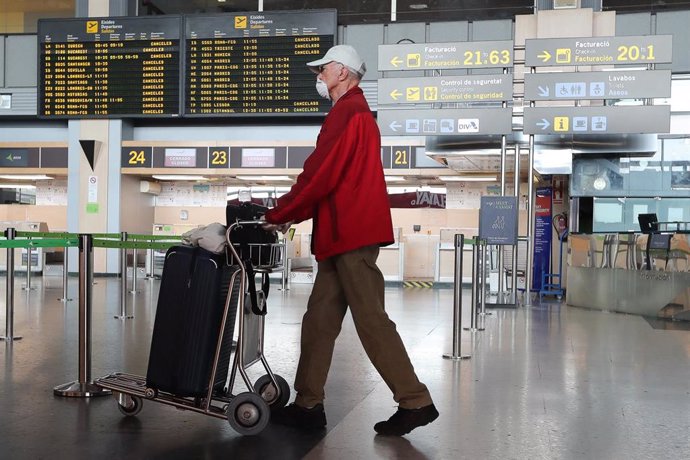 Una persona con mascarilla anda con un carrito con su equipaje  en el Aeropuerto de Valencia  durante el cuarto día del estado de alarma por coronavirus