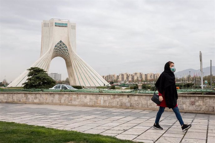 Una mujer con mascarilla camina por Teherán