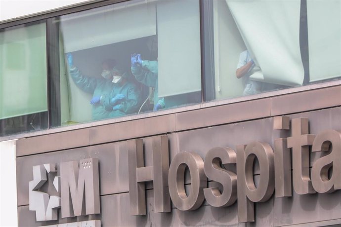 Sanitarios del Hospital de La Paz totalmente protegidos saludan y agradecen el apoyo desde una de las ventanas del centro donde se lucha contra el coronavirus, en Madrid.